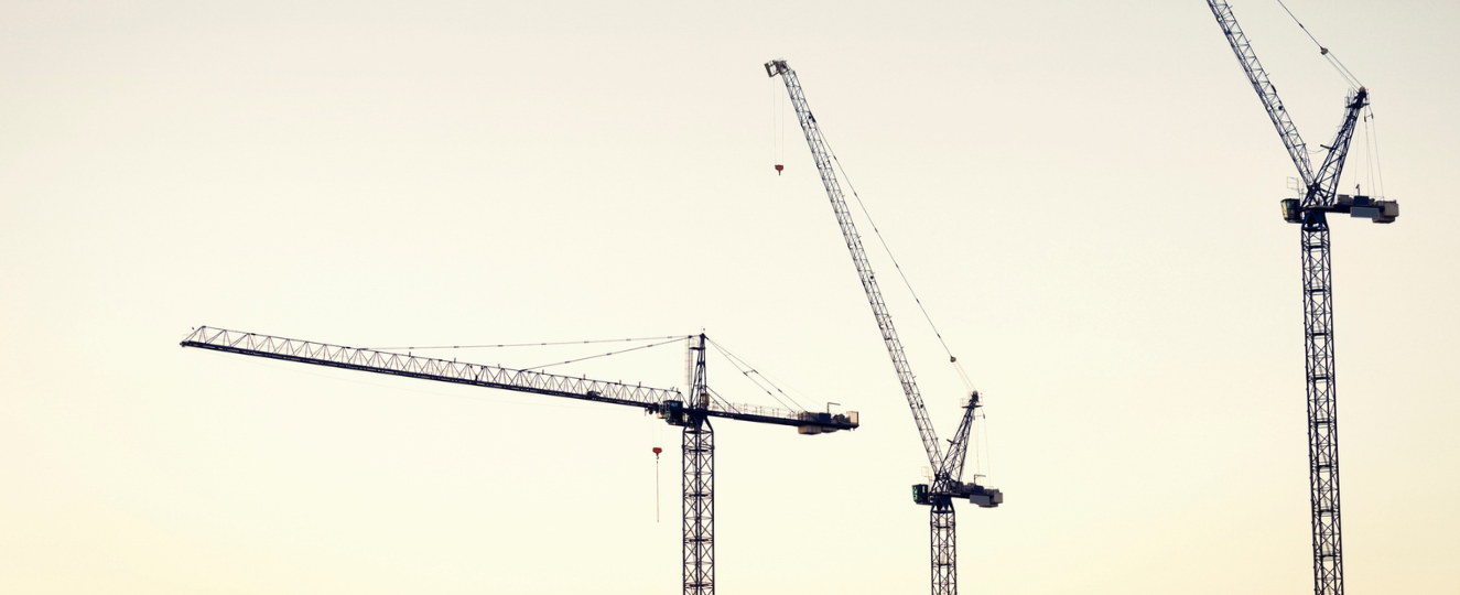 Three tower cranes with the sunset in the background