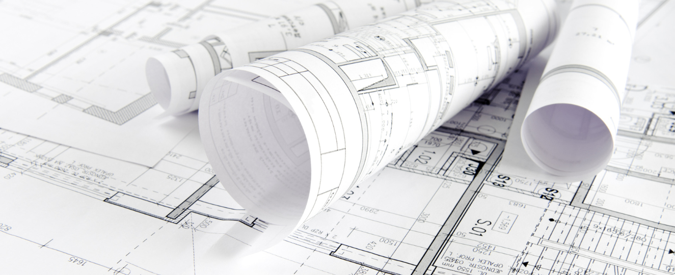 Architectural drawings on a table, with two rolled up on top