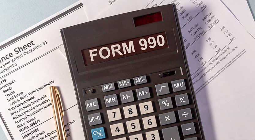 Calculator reading form 990, on top of tax documents