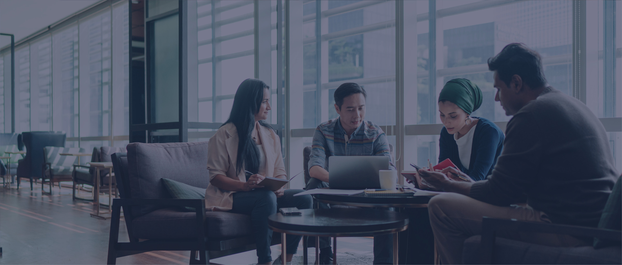 Four people gathered around a laptop in an office review materials.