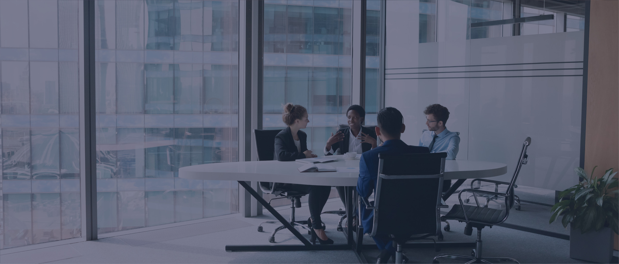 Group of people sitting in a conference room with a large window behind them.