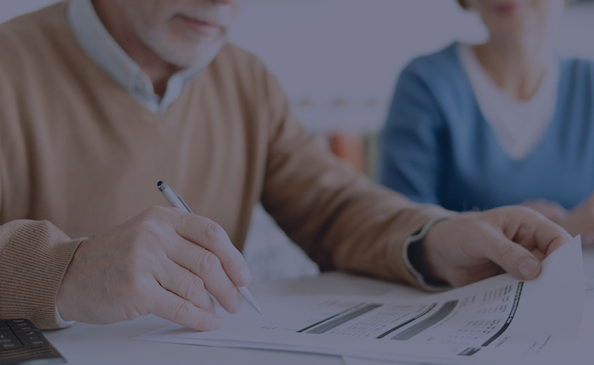 Two people reviewing paperwork and preparing to sign