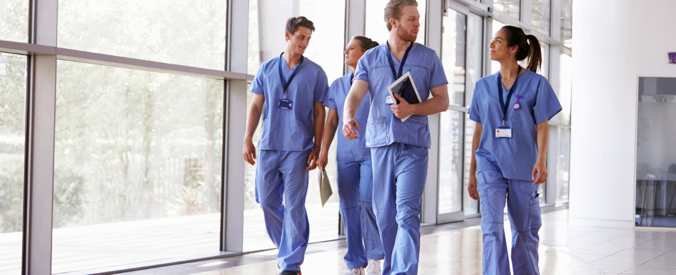 Four healthcare workers in scrubs walking in corridor