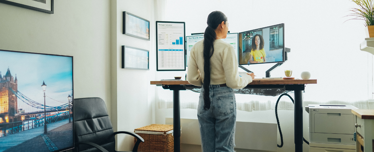 Person working from home in front of three computer monitors.