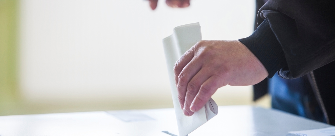 Person putting a ballot into a ballot box.